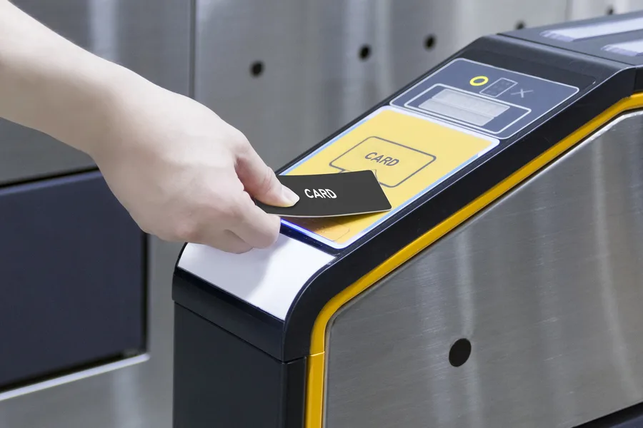 Hand presenting a contactless card to the reader of an access gate